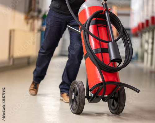 Man moves a wheeled fire-extinguisher.