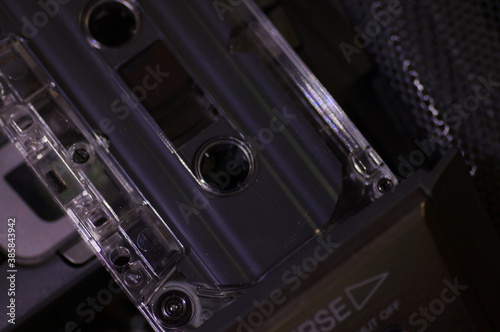 Audio cassette - in a dark light, against the background of a tape recorder.