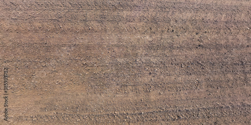 view from above on surface of gravel road with car tire tracks