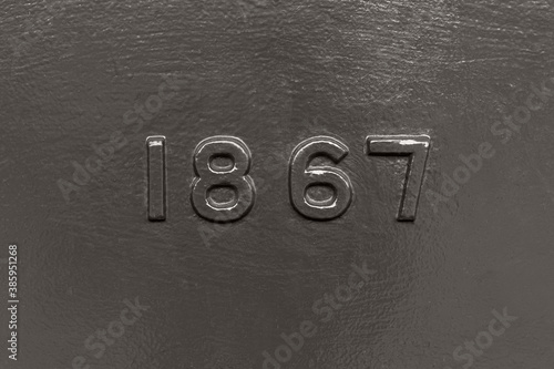 Old fashioned dark grey cast iron metal year 1867 with a seamless background.