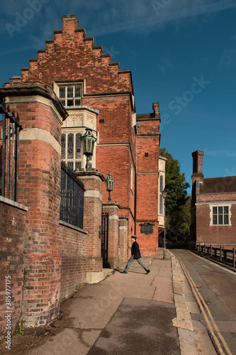 Harrow School building and a passing by young student, Greater London, UK 