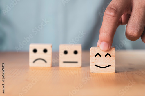 Select emotion or mood concept , Hand holding smile face or happy face which print screen on wooden cube block.