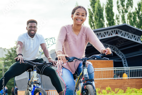 Laughing young couple riding bicycles in downtown