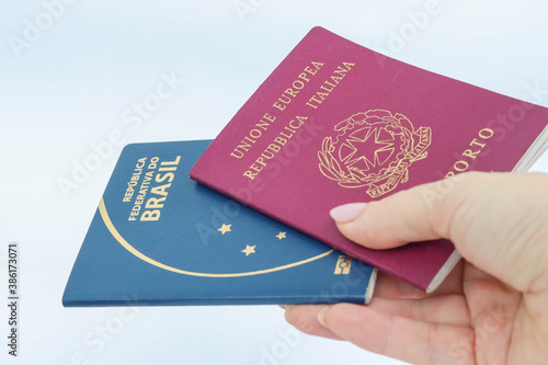 woman hand holding italian and brazilian passport - showing or delivering- dual citizenship concept