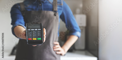 noncash payment - waitress with apron standing in cafe with pos terminal in hand. copy space