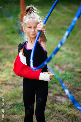 Girl gymnast in plaster cast on arm catching her hoop