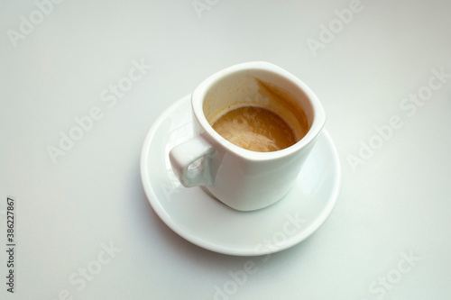 Isolated shot of a half full cup of coffee with milk on white background