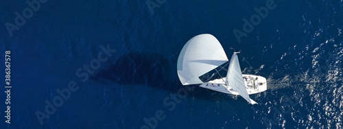Aerial drone ultra wide panoramic photo with copy space of beautiful sailboat with white sails cruising deep blue sea near Mediterranean destination port