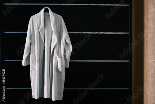 White robe in the hotel room. The hotel bathrobe weighs on a black cabinet