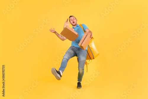 Delivery guy in blue uniform slipped and lost his balance and threw boxes of food from restaurant in direction. Clumsy food delivery guy broke up an order for customer. Poor product delivery