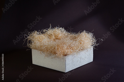 Gift box with wood wool, add your products. Empty gift package background with filler material.