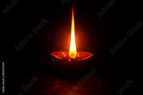 Diwali Diya in black. Deepam oil lamp. Flame in dark. a light powered by coconut oil.