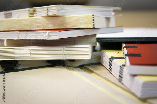 Close up photography of a pile of semifinished bound books in selective focus. Class work of printing students.