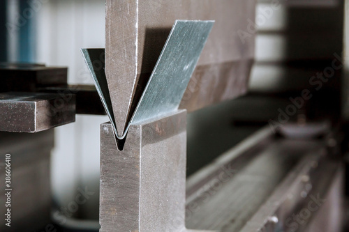 Bending sheet metal on a hydraulic machine at the factory. Bend tools, press brake punch and die. Close-up.