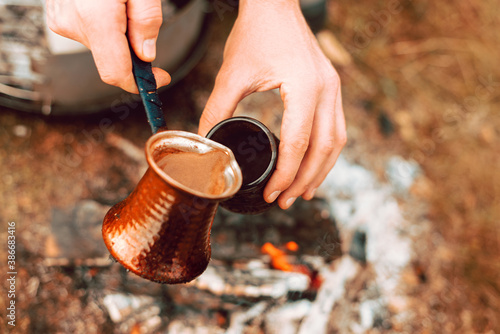 Close up photo on a turkish coffee pot pouring in a cup on a field in the morning