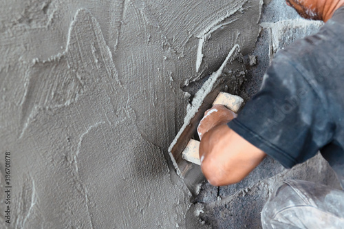 closeup hand of worker plastering cement at wall in construction site