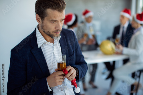 Sad businessman feeling left out from his colleagues during Christmas party in the office.