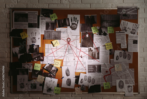 Detective board with fingerprints, photos, map and clues connected by red string on white brick wall