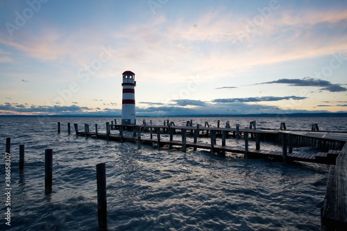 Lighthouse at the end of jetty on the shores of a large lake during dusk 