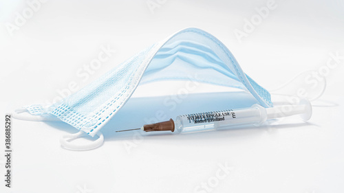 Covid 19 - maski koloru niebieskiego i strzykawka z igłą na białym tle. Maski i strzykawka izolowane makro