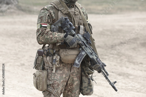 Soldier with machine gun and flag of Sudan on military uniform. Collage.