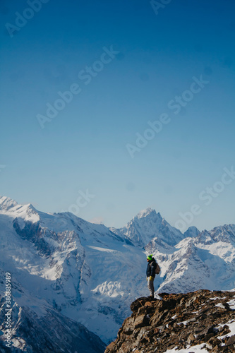 A man on a snowy mountain peak. Landscape on Dombai.