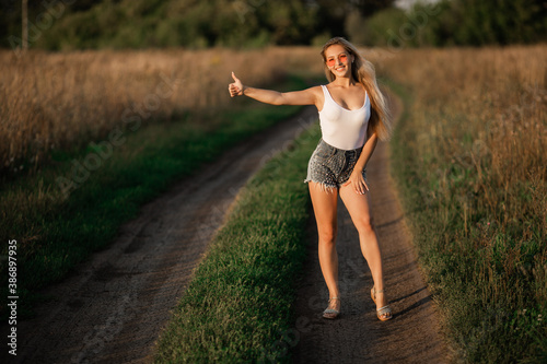 beautiful young female on the road hitchhiking