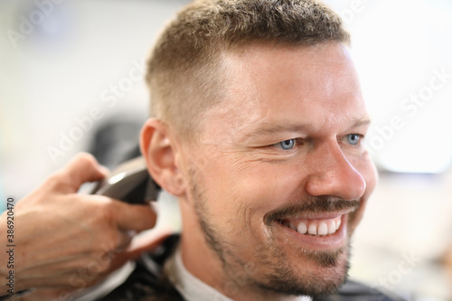 Smiling man who has haircut at barbershop. Courses and training for hairdressers concept
