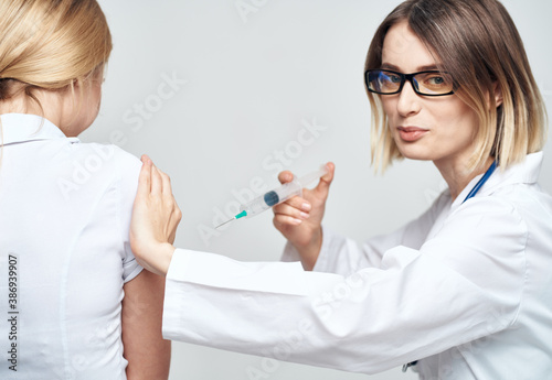 A woman doctor in a medical gown is giving an injection to a patient