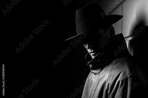 dark portrait of a man in a raincoat with a hat at night on the street