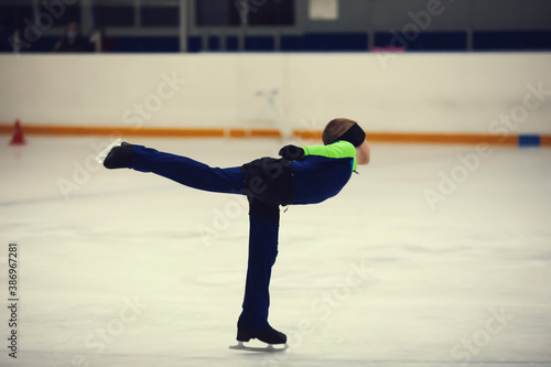 Figure skating school. Young figure skater practicing spiral at indoor skating rink. Kid learning to ice skate.