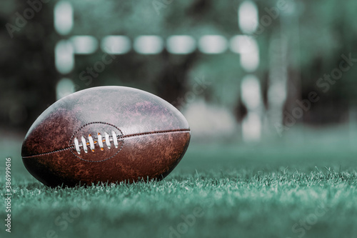 American football, rugby ball on green grass field background. Vintage color filter