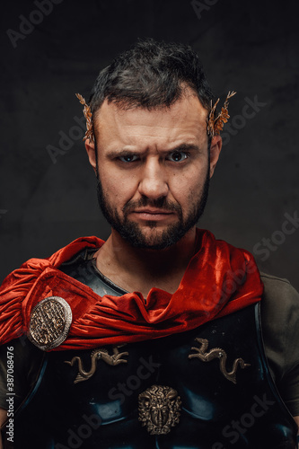 Serious and bearded roman emperor dressed in dark armour and red cloak