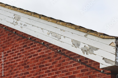 Flaking paint on wooden fascia boards to a side of a brick built building