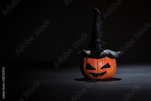 Cabeza de calabaza con ojos, boca y sombrero de bruja sobre fondo negro y espacio para agregar texto. Calabaza de Halloween. Decoración noche de brujas.