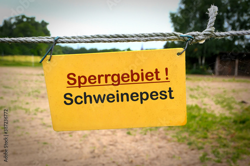 Schild mit der Aufschrift "Sperrgebiet Schweinepest" an einem Zaun zu einem Bauernhof 