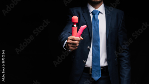 man in a suit is holding pink vibrators for sex