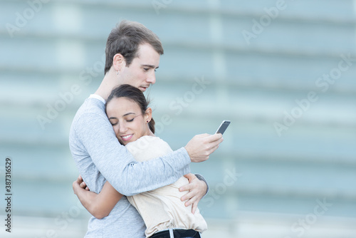 Digital addiction concept. A young couple hughing while the boy is checking his smartphone