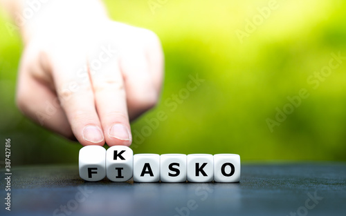 Hand dreht Würfel und ändert den Ausdruck "Fiasko" in "Kasko".