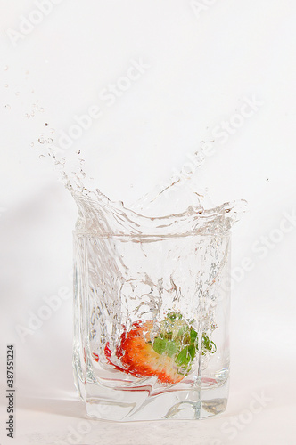 truskawki wpadające do szklanki z wodą