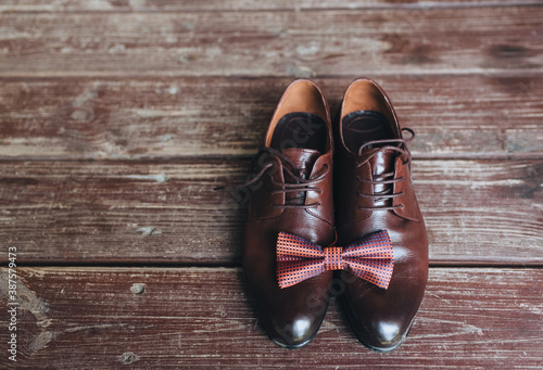 Close-up of leather brown shoes with a bow-tie on a wooden background. Gentleman's, men's set. Business. Wedding shoes, details. Photography, conception.