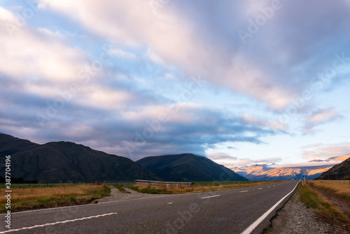 A long straight road with raining cloud and Mountain in evening