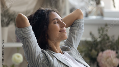 Close up of young Caucasian woman rest hands over head daydream or visualize relieve negative emotions. Happy calm millennial female relax with eyes close, meditate or sleep. Stress free concept.