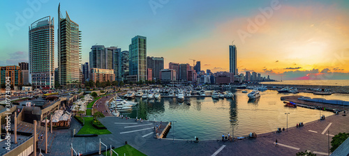 A panoramic photo of Beirut, Lebanon city skyline at sunset, featuring a marina with boats and a scenic waterfront walk. 