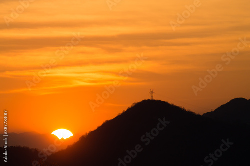 Outline of mountains at sunset with electric pylon