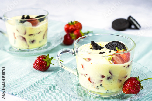 Zabaglione with strawberries and chocolate cookies on a blue napkin