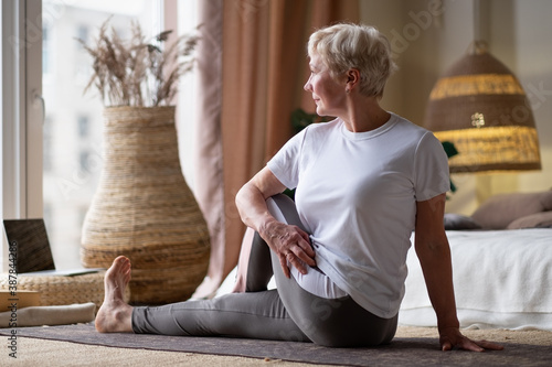 Senior caucasian woman in half spinal twist pose on mat