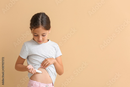 Little diabetic girl giving herself insulin injection on color background