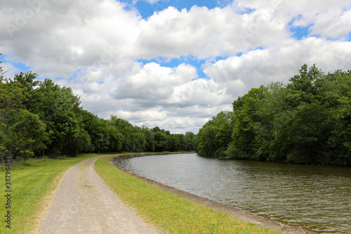 Tow path on the Erie Canal at Medina, New York. Curve on the tree lined canal on a cloudy spring day.