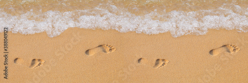 Texture background Footprints of human feet on the sand near the water on the beach